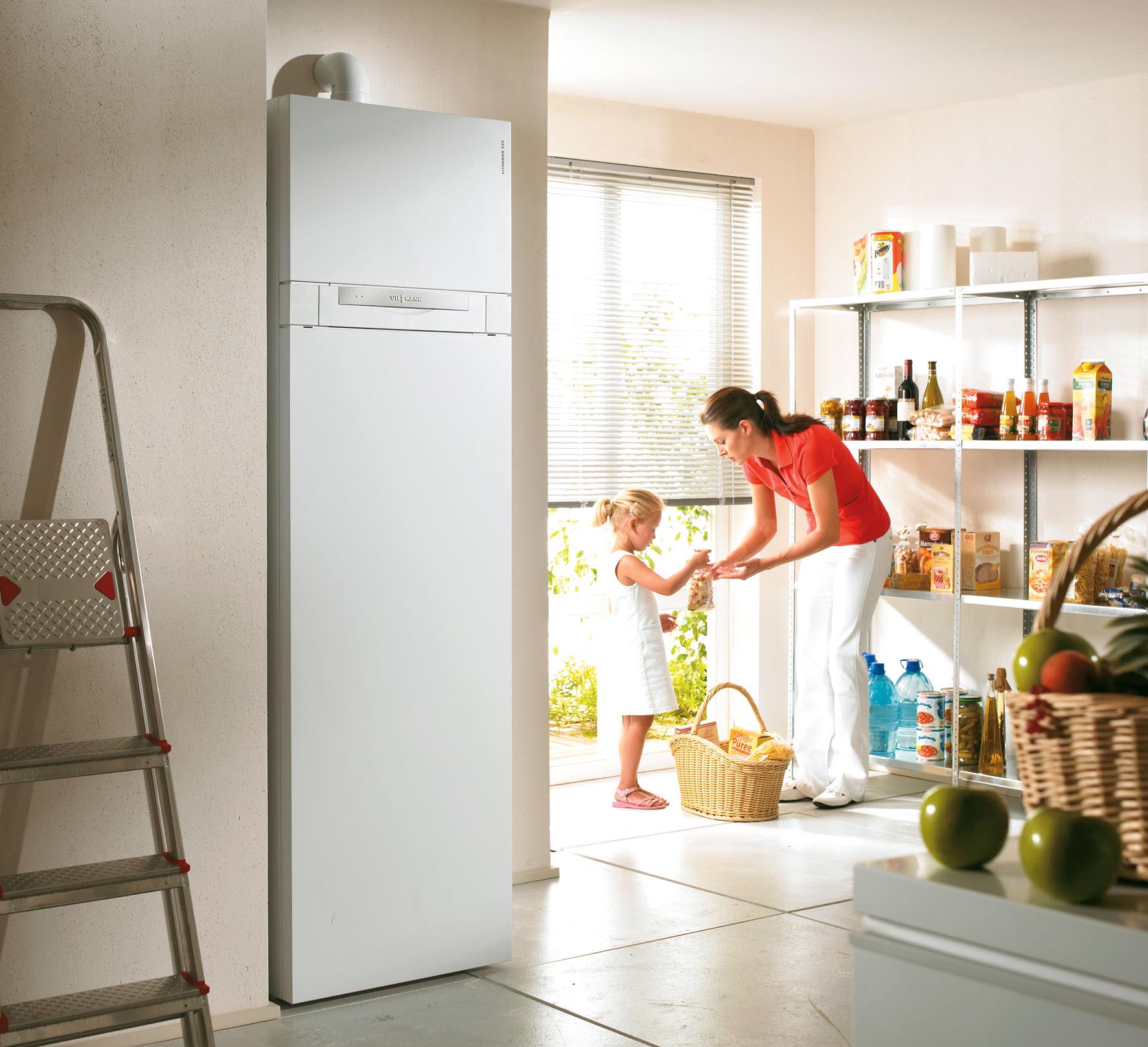 Frau und Kind stehen in einem Hauswirtschaftraum mit einer Heizungsanlage im Vordergrund